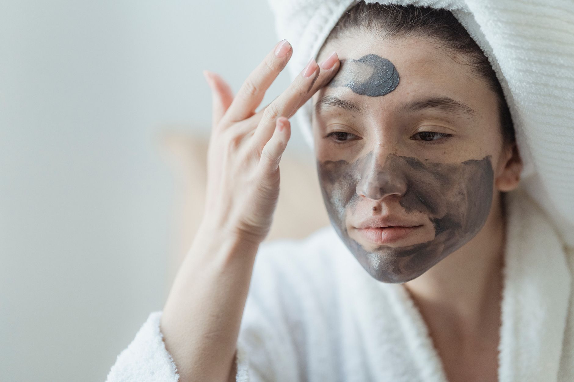 Woman applying a green clay mask to her face