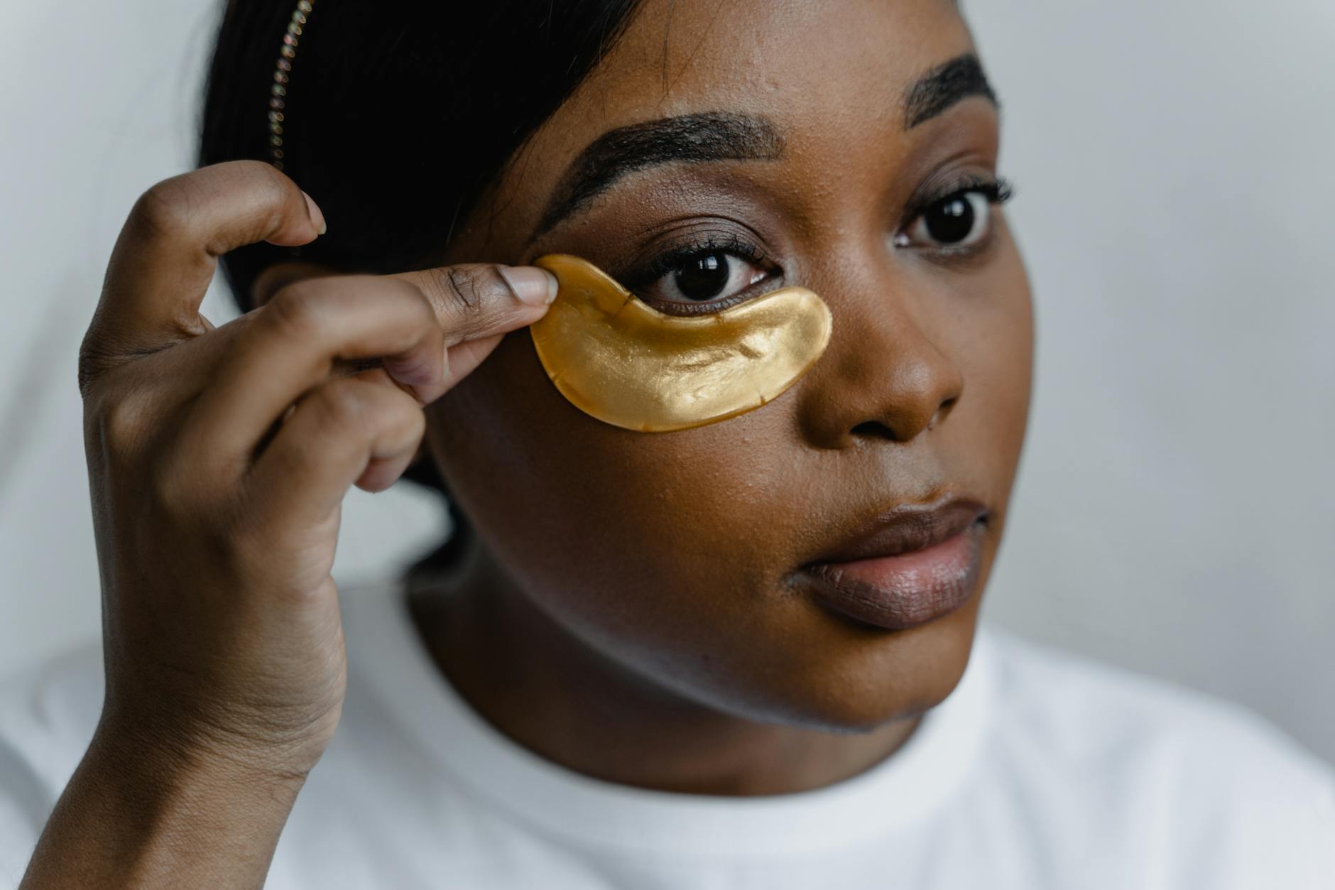 Close-up of a woman applying eye cream to her under-eye area, demonstrating skincare routine.