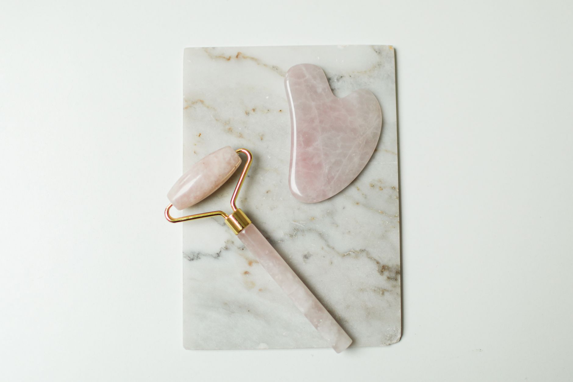 Woman performing gua sha facial massage with a rose quartz tool