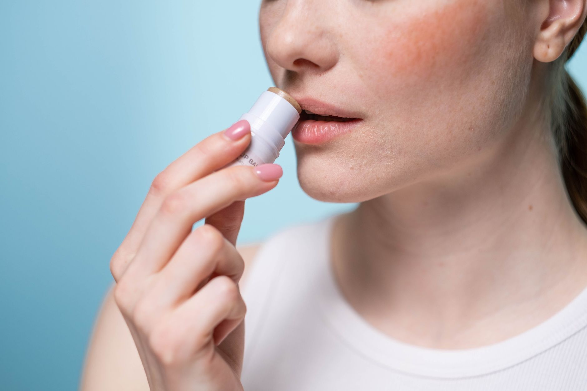 A woman applying lip balm to her lips
