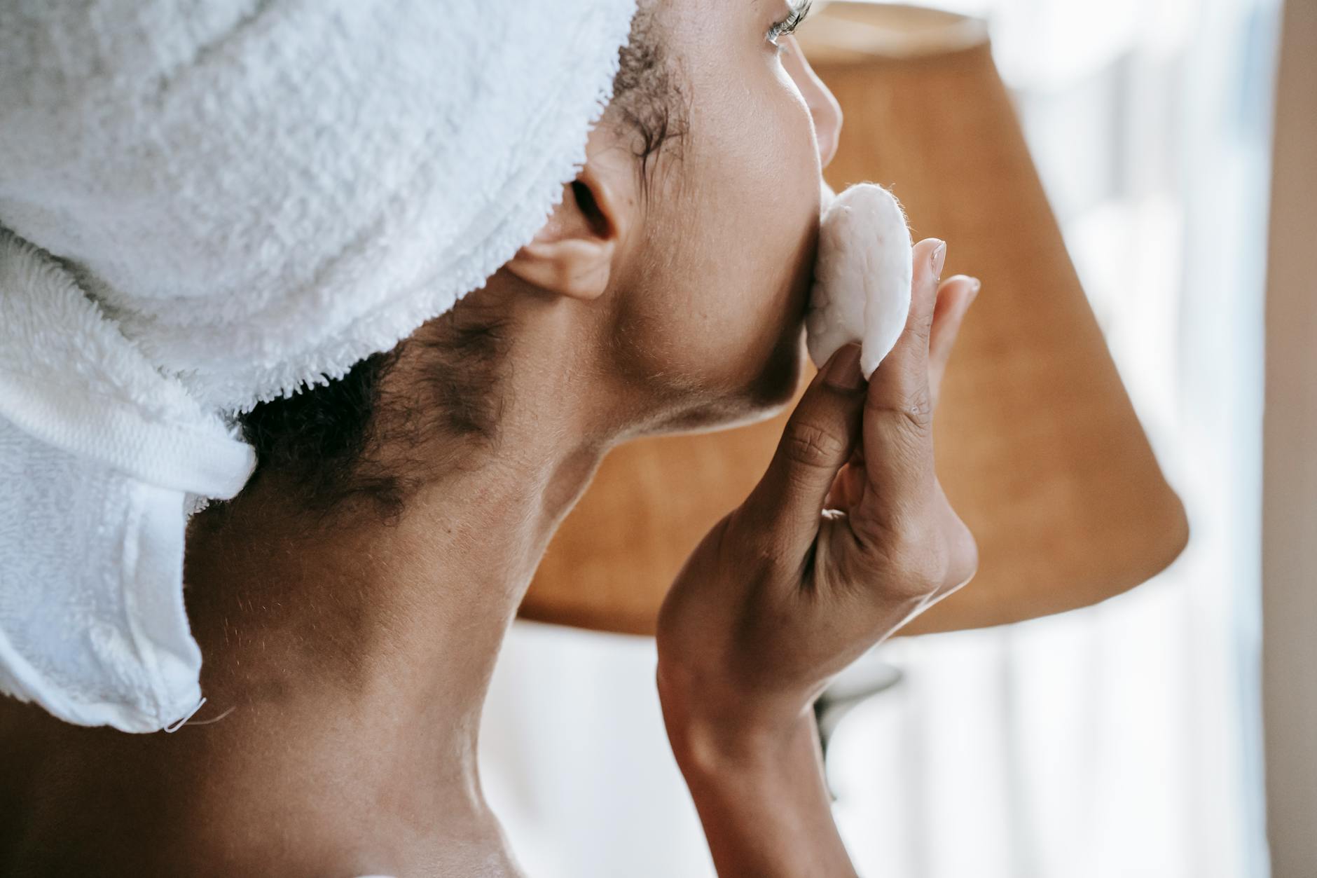A woman gently applying moisturizer to her face with a calm expression.